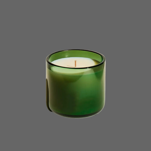 
Green candle in a glass container on a beige background